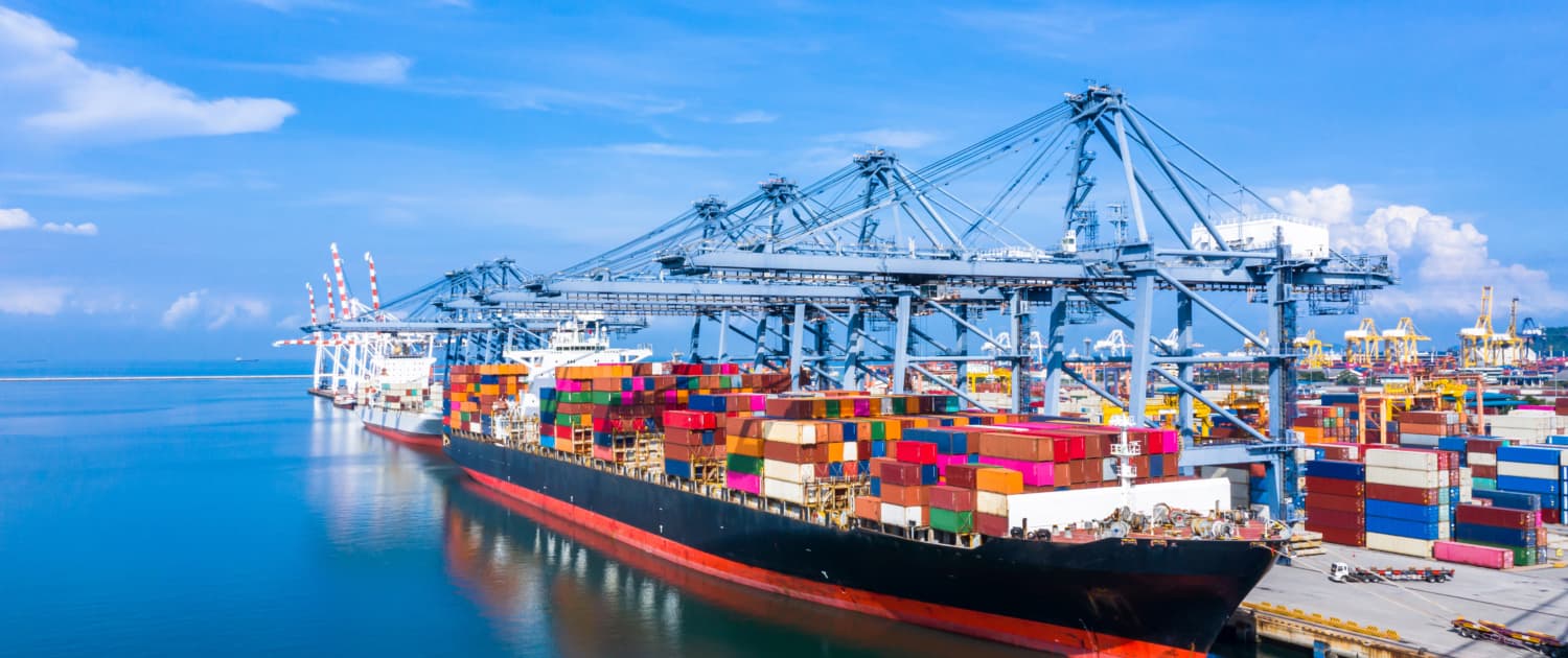 Aerial view of a busy sea port with cranes and ships.