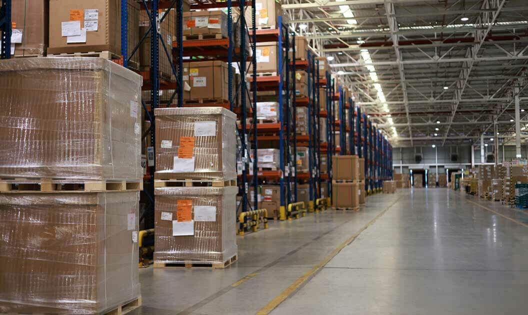 A forklift moving pallets in a spacious warehouse.